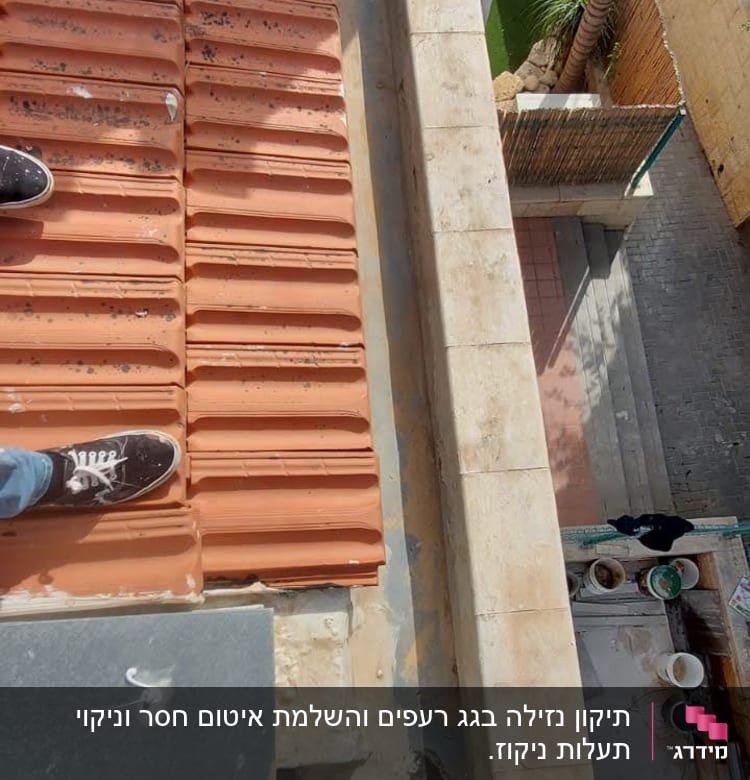 רגליים על גג רעפים אדומים עם קיר אבן בצד